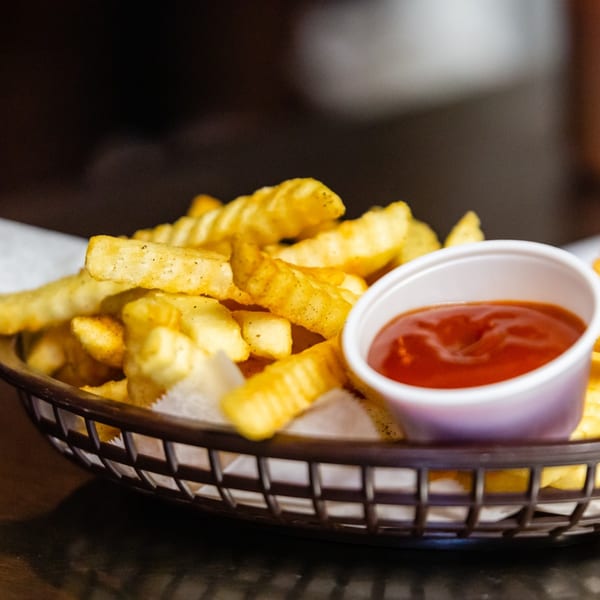 A basket of golden crinkle-cut fries with a side of ketchup, ready to be enjoyed.